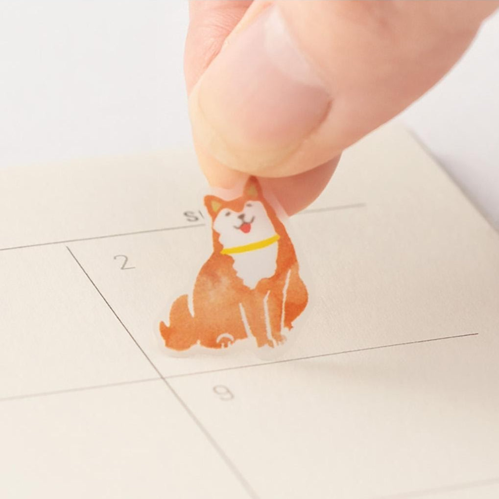 Small dog-shaped stamp being pressed onto a surface with a hand visible.