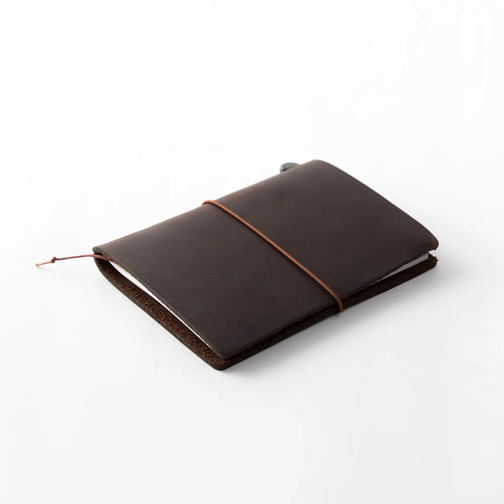 TRAVELER’S notebook Passport Size in Brown – leather cover with elastic closure, shown with accessories including cotton bag, refill, and spare band.