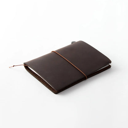 TRAVELER’S notebook Passport Size in Brown – leather cover with elastic closure, shown with accessories including cotton bag, refill, and spare band.
