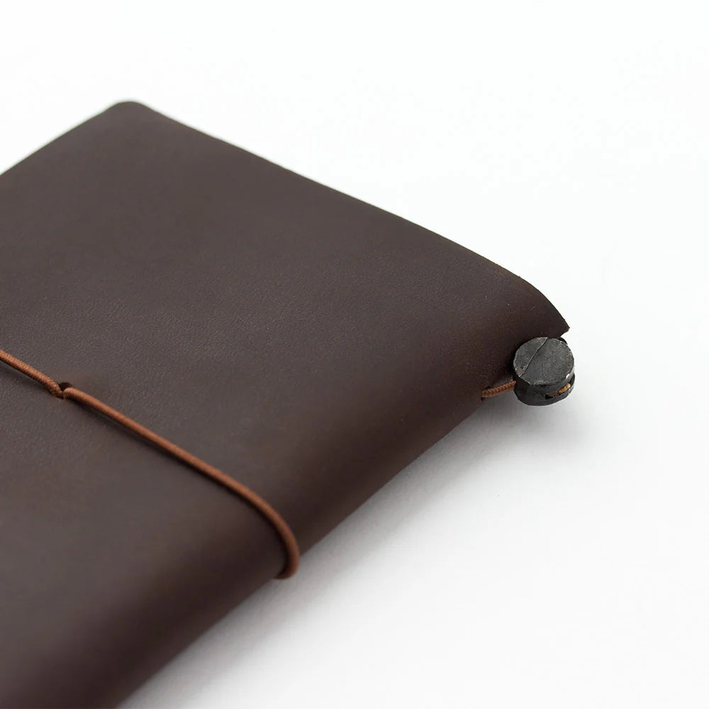 TRAVELER’S notebook Passport Size in Brown – leather cover with elastic closure, shown with accessories including cotton bag, refill, and spare band.
