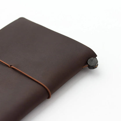 TRAVELER’S notebook Passport Size in Brown – leather cover with elastic closure, shown with accessories including cotton bag, refill, and spare band.