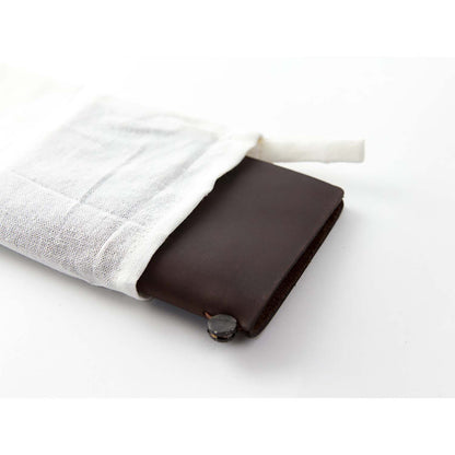 TRAVELER’S notebook Passport Size in Brown – leather cover with elastic closure, shown with accessories including cotton bag, refill, and spare band.