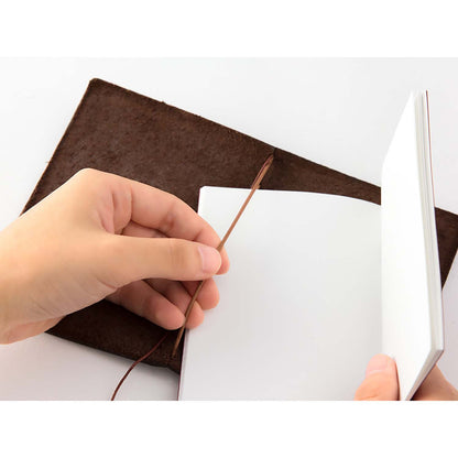 TRAVELER’S notebook Passport Size in Brown – leather cover with elastic closure, shown with accessories including cotton bag, refill, and spare band.
