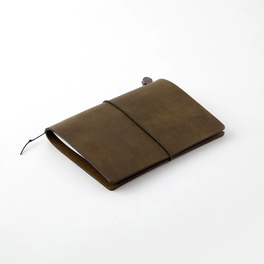 TRAVELER’S notebook in Olive – a dark brownish-green leather cover with earthy, rugged tones that deepen and develop a rich patina over time. Includes cotton bag, blank refill, and spare band.