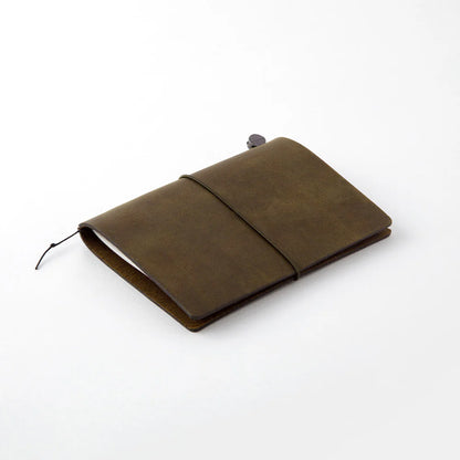 TRAVELER’S notebook in Olive – a dark brownish-green leather cover with earthy, rugged tones that deepen and develop a rich patina over time. Includes cotton bag, blank refill, and spare band.