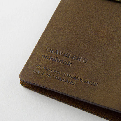 TRAVELER’S notebook in Olive – a dark brownish-green leather cover with earthy, rugged tones that deepen and develop a rich patina over time. Includes cotton bag, blank refill, and spare band.