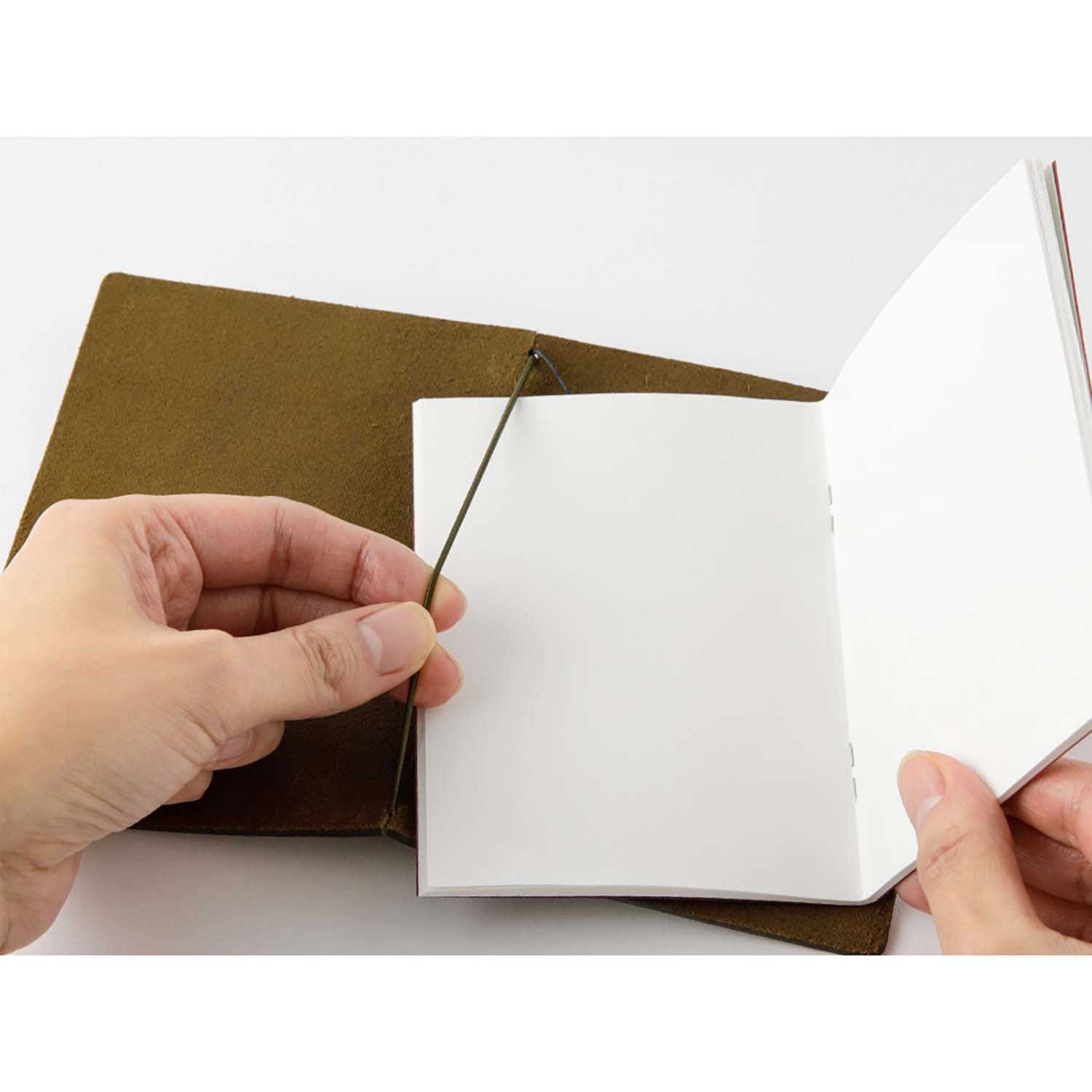 TRAVELER’S notebook in Olive – a dark brownish-green leather cover with earthy, rugged tones that deepen and develop a rich patina over time. Includes cotton bag, blank refill, and spare band.
