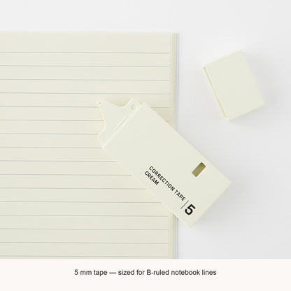 Midori cream correction tape beside a lined notebook, with an English caption explaining the 5mm tape width