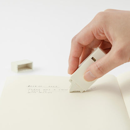 Hand applying Midori cream correction tape to paper