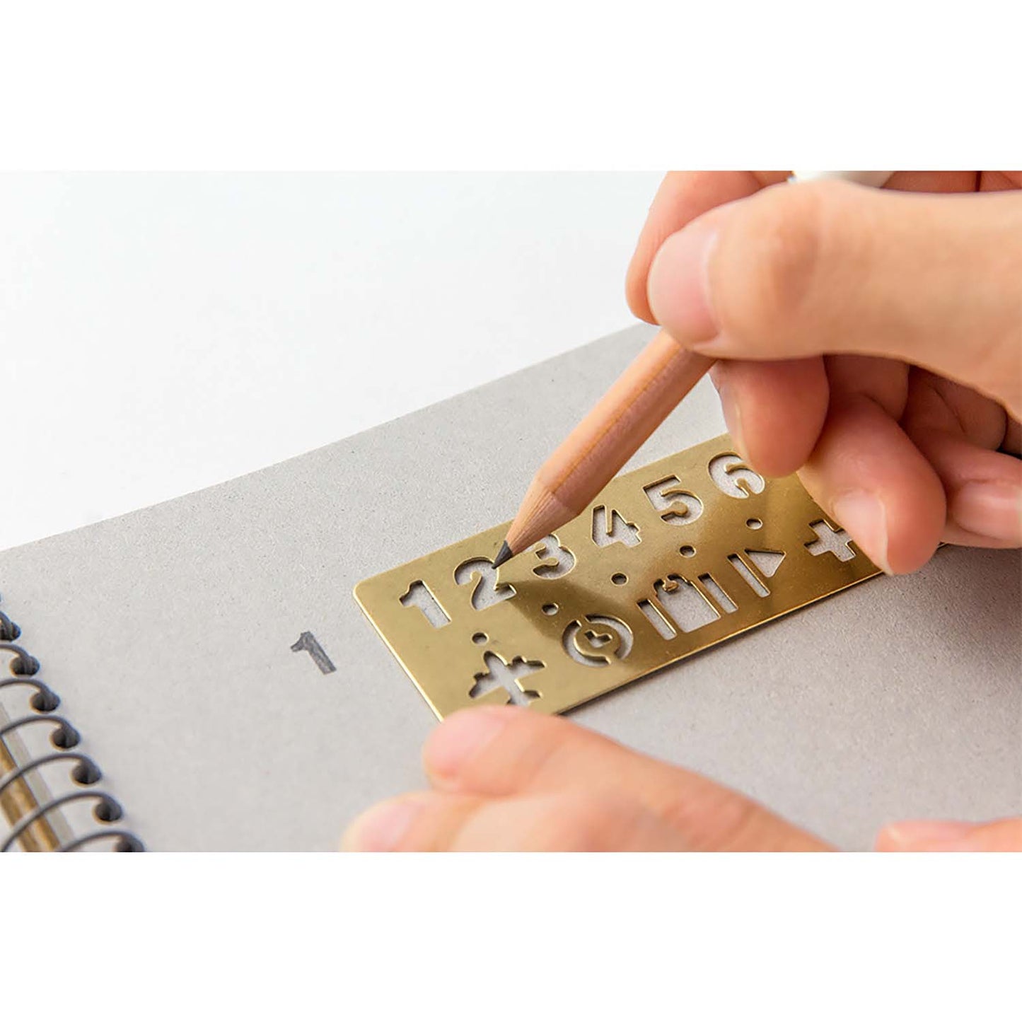 Traveler’s Company brass stencil bookmark with numbers and travel-themed icons