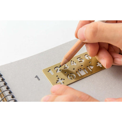 Traveler’s Company brass stencil bookmark with numbers and travel-themed icons