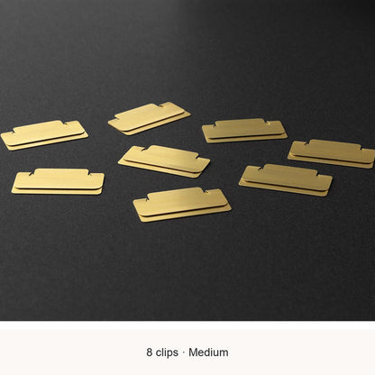 Eight Midori Chiratto medium brass index clips, with English feature captions