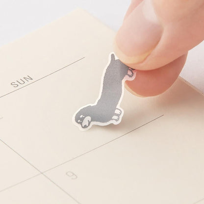 Hand holding a small dog-shaped sticker over a calendar