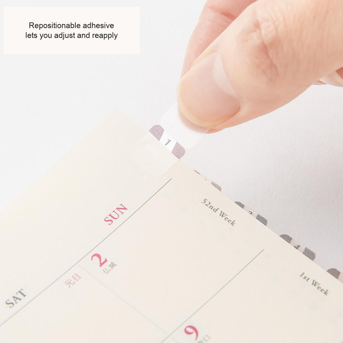 Hand placing a Midori Chiratto number tab on a planner page, with English feature captions
