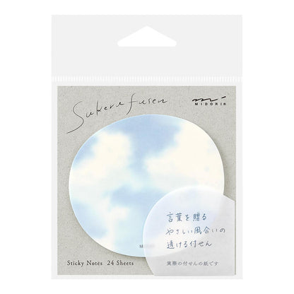 A hand peeling a translucent sticky note from a circular sky-themed pad with cloud design
