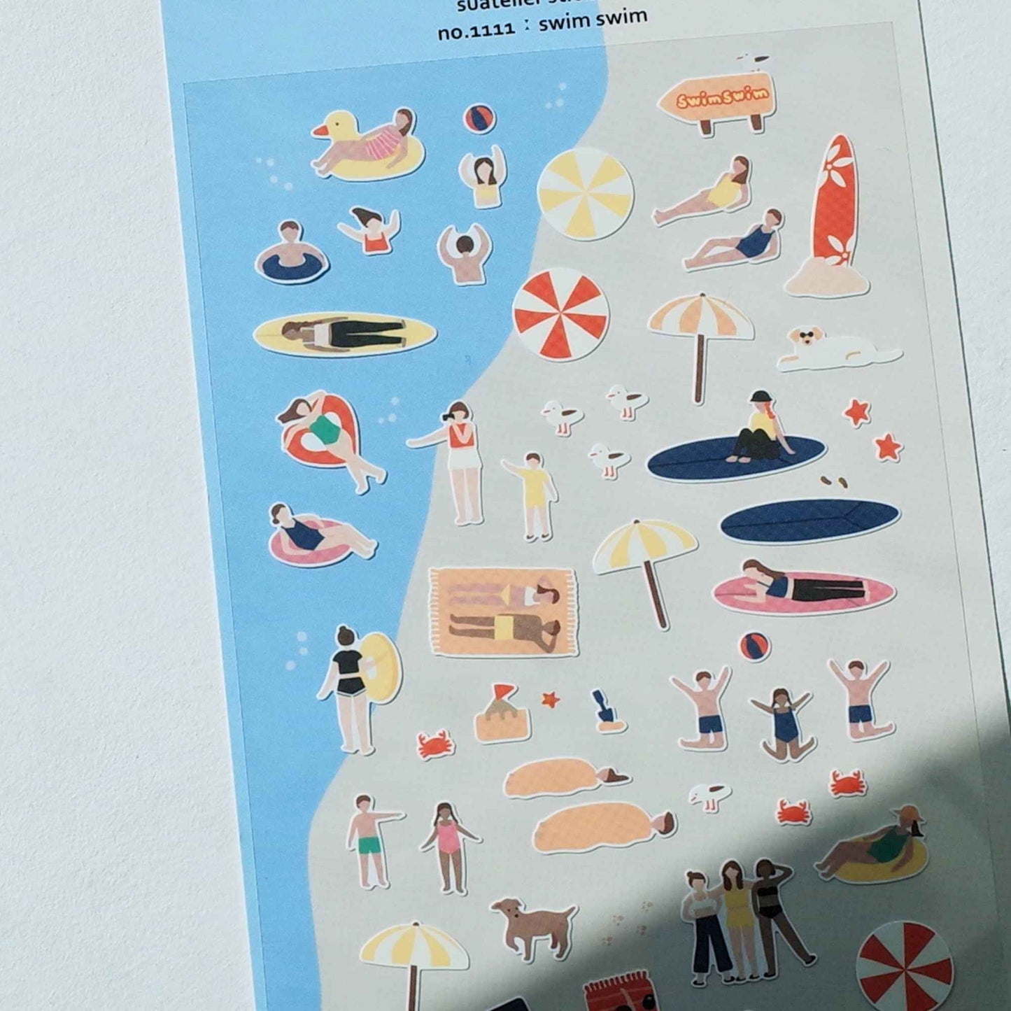 Suatelier Swim Swim sticker sheet featuring beach scenes, swimmers, surfboards, umbrellas and summer holiday illustrations.